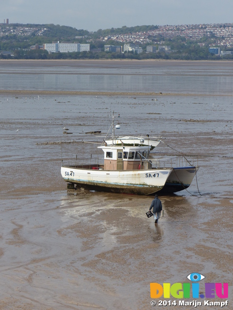 FZ005344 Man walking to boat on mud flats